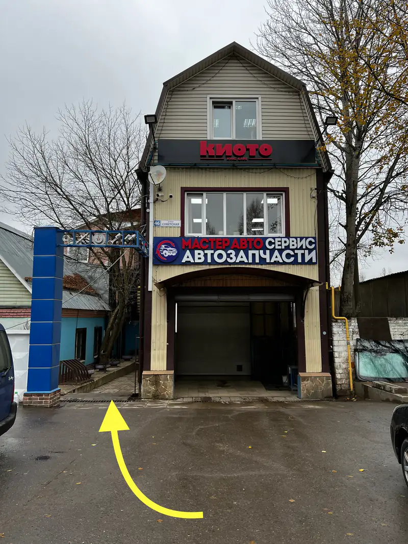 Вход во двор на Советской, 46: здание с вывеской «Мастер Авто Сервис — Автозапчасти», стрелка показывает проезд слева